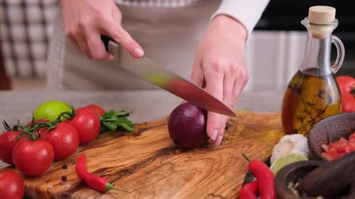Woman Cutting Red Onion on Wooden Board