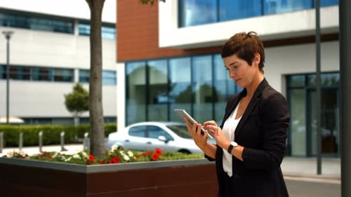 Professional Woman Using Tablet Outside Modern Office
