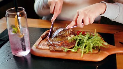 Person Cutting Into Steak with Knife and Fork