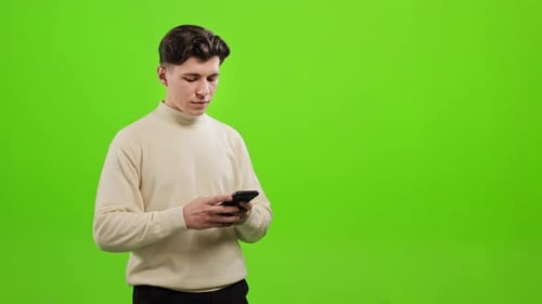 Man is Standing and Texting on His Smartphone