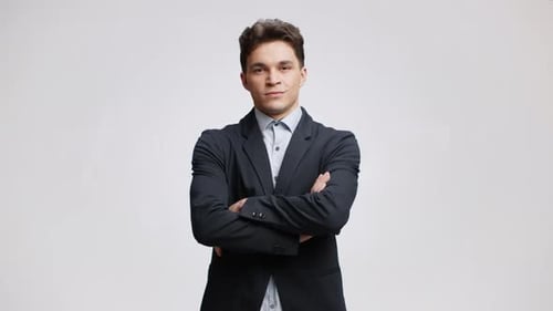 Studio Portrait of Young Confident Top Manager Wearing Formal Suit Posing to Camera with Folded Arms