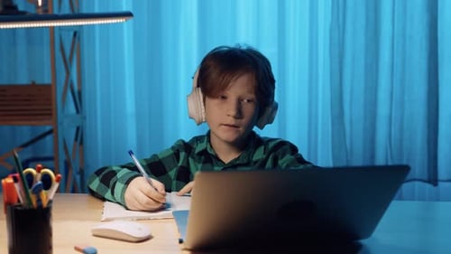 Focused Child Studying at Desk with Laptop