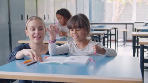 Happy Friendly School Teacher and Pupil Girl at Desk