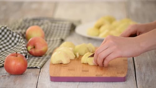 Hands slice ripe apples on cutting board