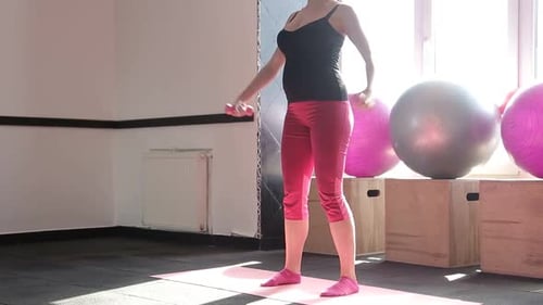 Pregnant Woman Sitting on Yoga Mat and Performs Warmup on White Background