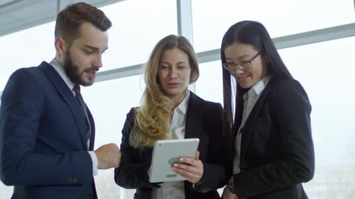 Professionals Collaborating on Tablet in Modern Office