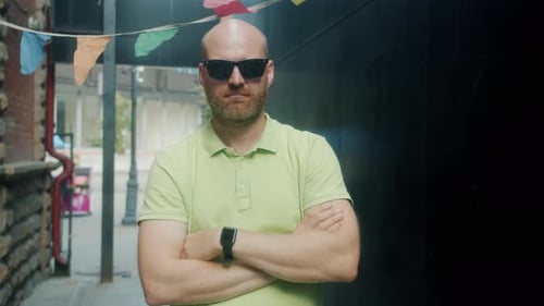 Man Takes Off Sunglasses on City Street