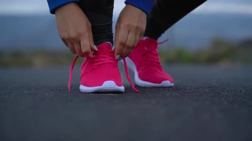 Running Shoes Woman Tying Shoe Laces on a Desert Road in a Mountainous Area