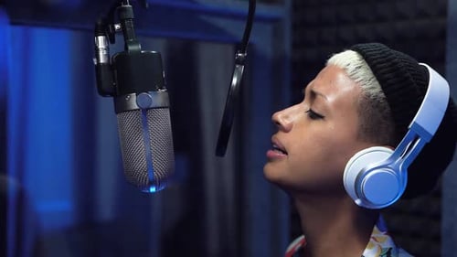 Young professional female singer recording a new song album inside music production studio