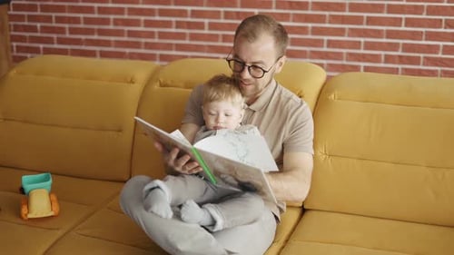 Man Reading Book with Young Child on Couch