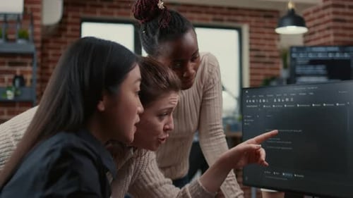 Programer Pointing at Computer Screen Explaining Running Code to Coworkers Brainstorming Software
