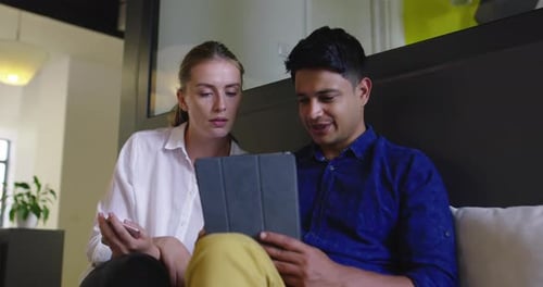 Coworkers Collaborate Using Tablet in Modern Office