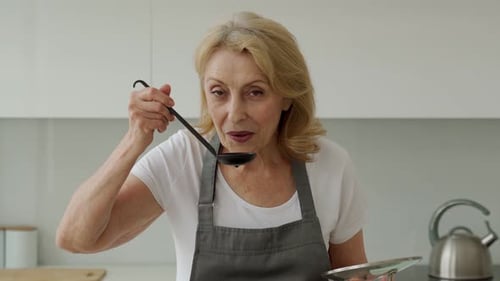 Woman Tastes Food with Ladle in Kitchen