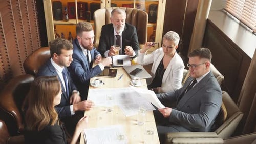 Solid Gray Headed Man Demonstrates Documentation To Colleagues in Bright Study.