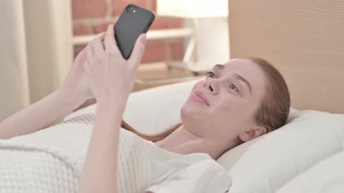 Woman Using Smartphone Lying in Bed