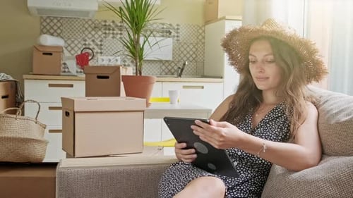 Woman Using Tablet Among Moving Boxes