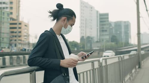 Young Adult Using Phone in City Wearing Face Mask