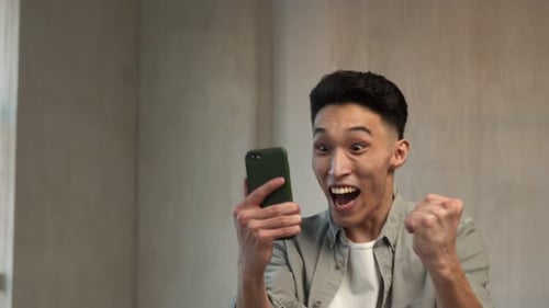 Young Adult Celebrates Financial Success with Smartphone