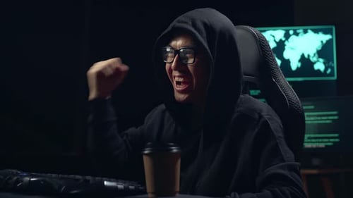 Asiatischer männlicher Hacker, der Computer hackt und feiert