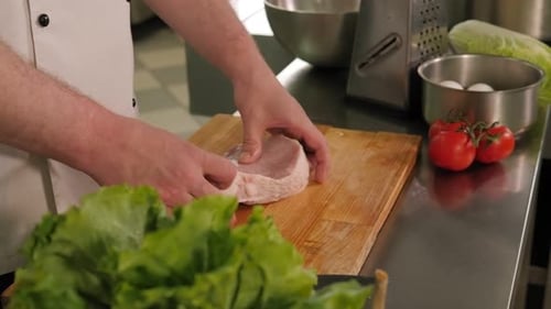 Closeup of a Chef Inspecting Fresh Meat Before Cooking a Steak in the Kitchen