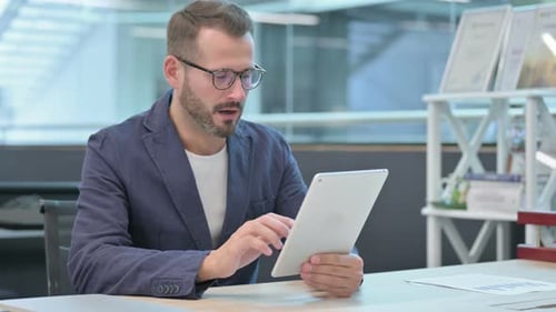Middle Aged Businessman Reacting to Loss on Tablet While Sitting in Office