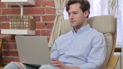 Man Using Laptop in Chair at Home