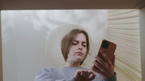 Young Woman Uses Phone from Inside Cardboard Box