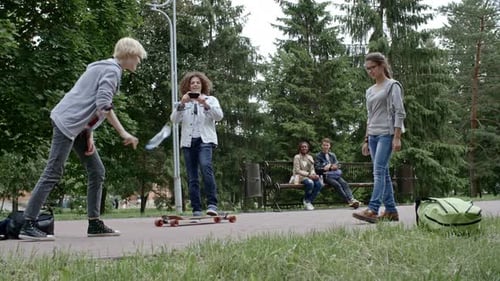 Teenagers Hanging Out in City Park with Longboard