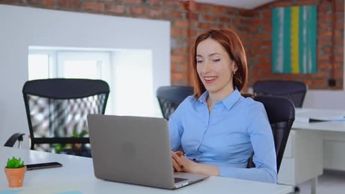 Woman Smiling Using Laptop in Modern Office