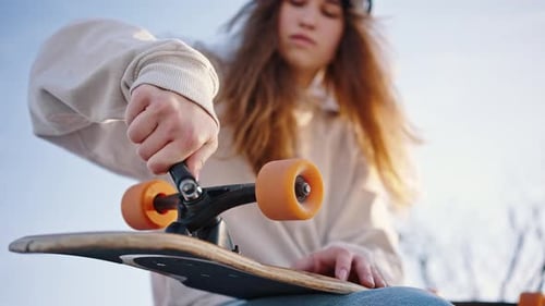 Girl Adjusting Skateboard Wheels Outdoors