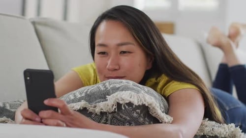 Woman on Couch Looks at Cellphone and Smiles