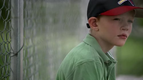 Slow motion pan of boy in baseball hat looking up.