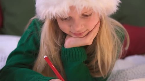 Child Writes Letter to Santa, Wearing Santa Hat