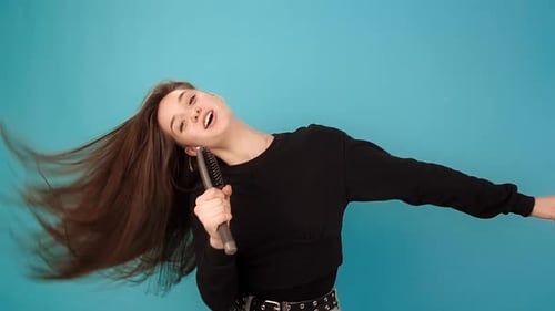 Le modèle chante dans la brosse à cheveux comme microphone