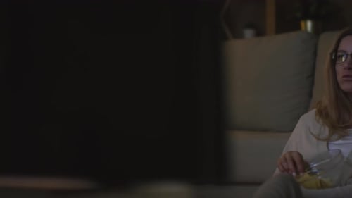 Woman in Glasses Eating Chips and Watching TV
