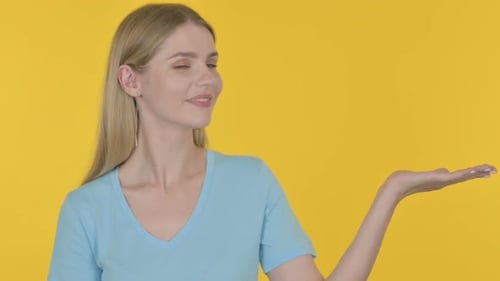 Woman Presents with Hand on Yellow Background