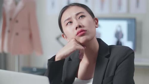 Close Up Of Asian Female Designer In Business Suit Working On A Laptop And Thinking While Designing