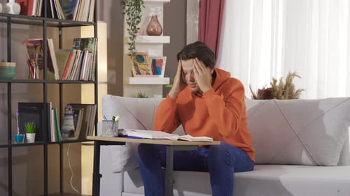 Young Student Studying and then Gets a Headache