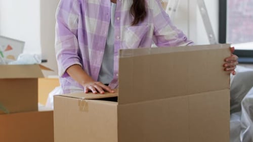 Woman Packing Cardboard Box for Moving at Home