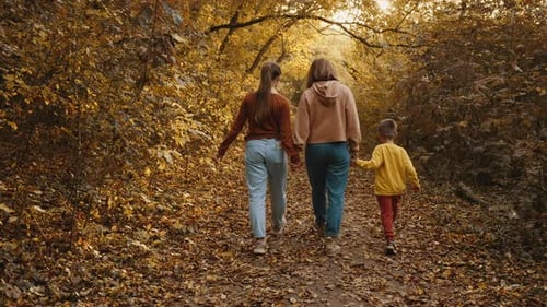 Mom Walks with Her Children in the Autumn Park