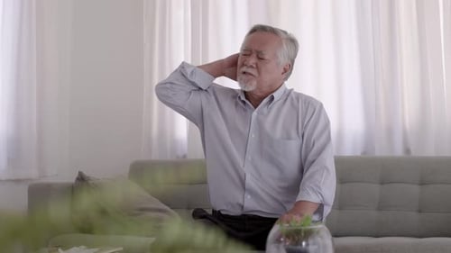 Senior Man Massaging Stiff Neck at Home