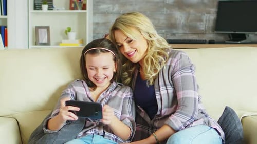 Mother and Child Enjoying Smartphone on Couch