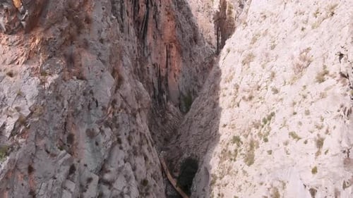 Drone flying through river canyon surrounded by rocky mountains.