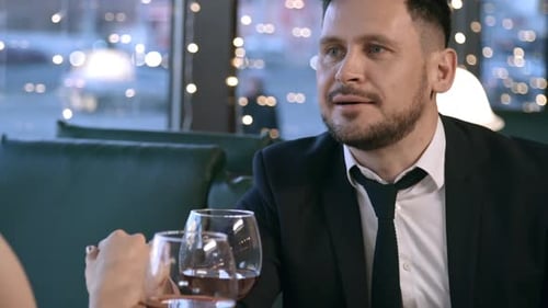 Romantic Couple Holding Hands Over Wine at Restaurant