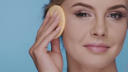 Beautiful Woman Using Makeup Sponge on Face