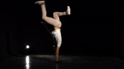 Junger Mann tanzt Breakdance im schwarzen Studio