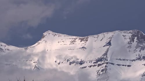 Clouds surrounding snow covered mountain peak