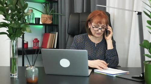Woman Works on Laptop and Talks on Phone