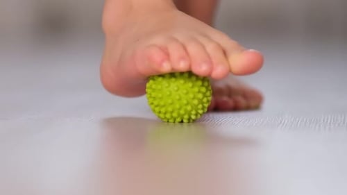 Child Foot Massaging Green Spiky Ball Close Up