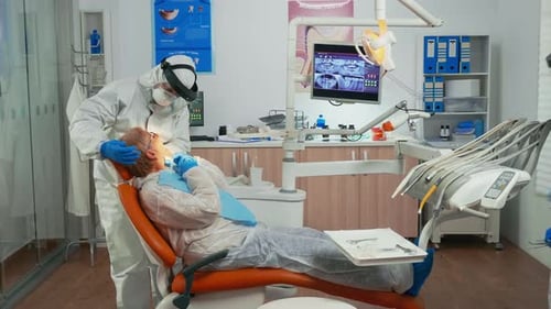 Dentist Examining Patient in Clinic with Protective Gear
